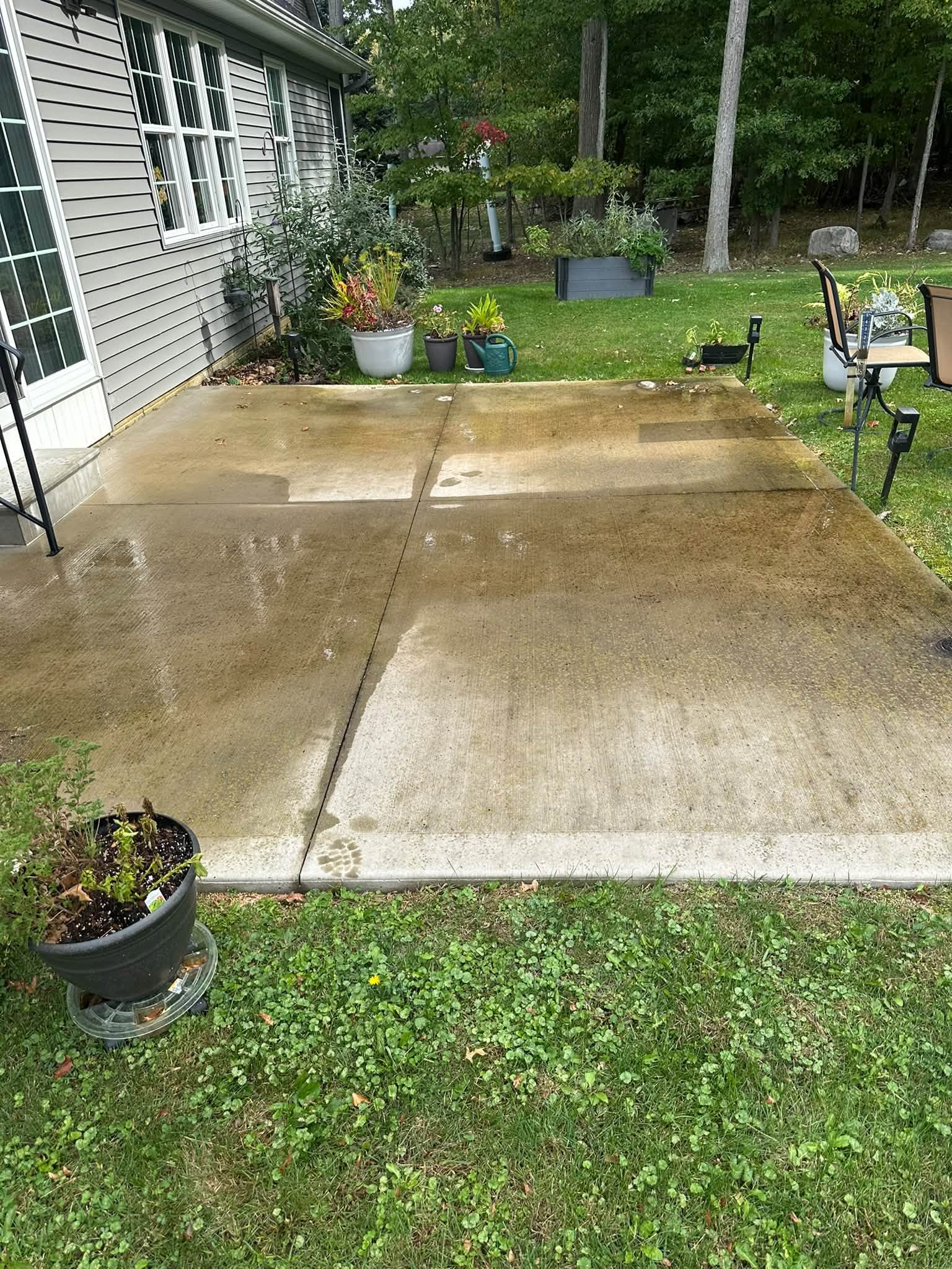 Before washing: darker buildup across the concrete patio